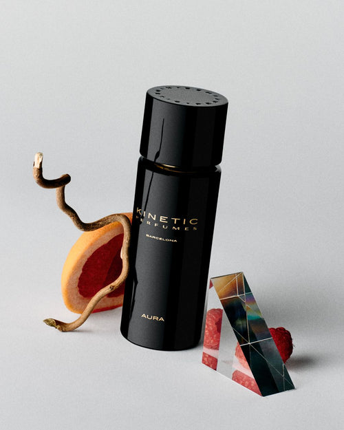 Kinetic Perfumes Aura Extrait de Parfum 100 ml – schwarzer Flakon mit Grapefruit, Ast, Glasprisma und Himbeeren auf Hellgrau