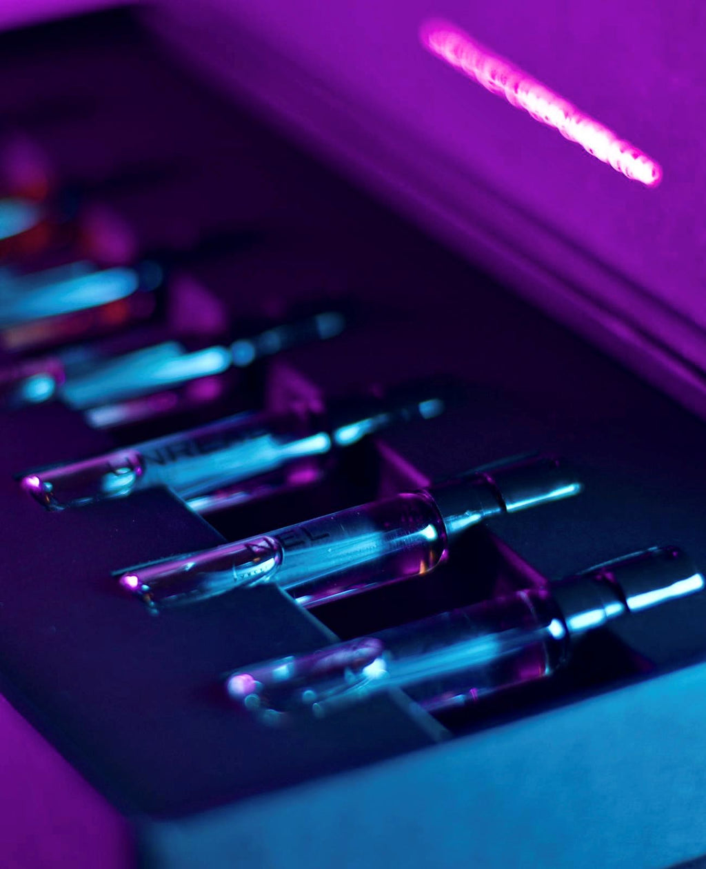 Kinetic Perfumes Discovery Set 11 × 2 ml – Probenfläschchen in Box unter violettem und türkisem Neonlicht