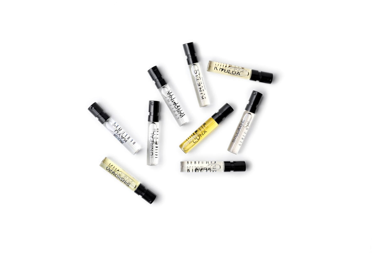 Kinetic Perfumes Discovery Set 11 × 2 ml – verstreute Probenfläschchen mit schwarzen Kappen auf Weiss