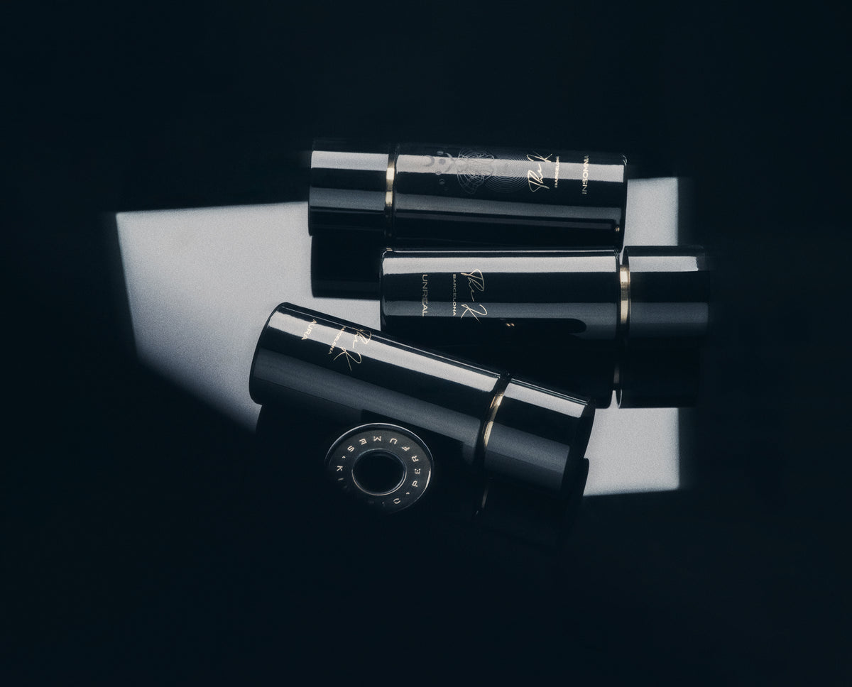 Drei schwarze Kinetic Perfumes Flakons mit Goldring im Lichtstreifen auf Schwarz