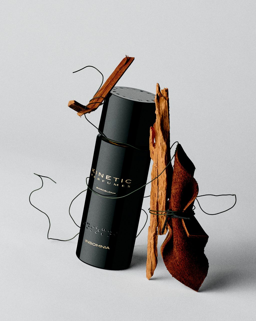 Kinetic Perfumes Insomnia Extrait de Parfum 100 ml – schwarzer Flakon mit Holzrinde, Wildleder und schwarzer Schnur auf Hellgrau