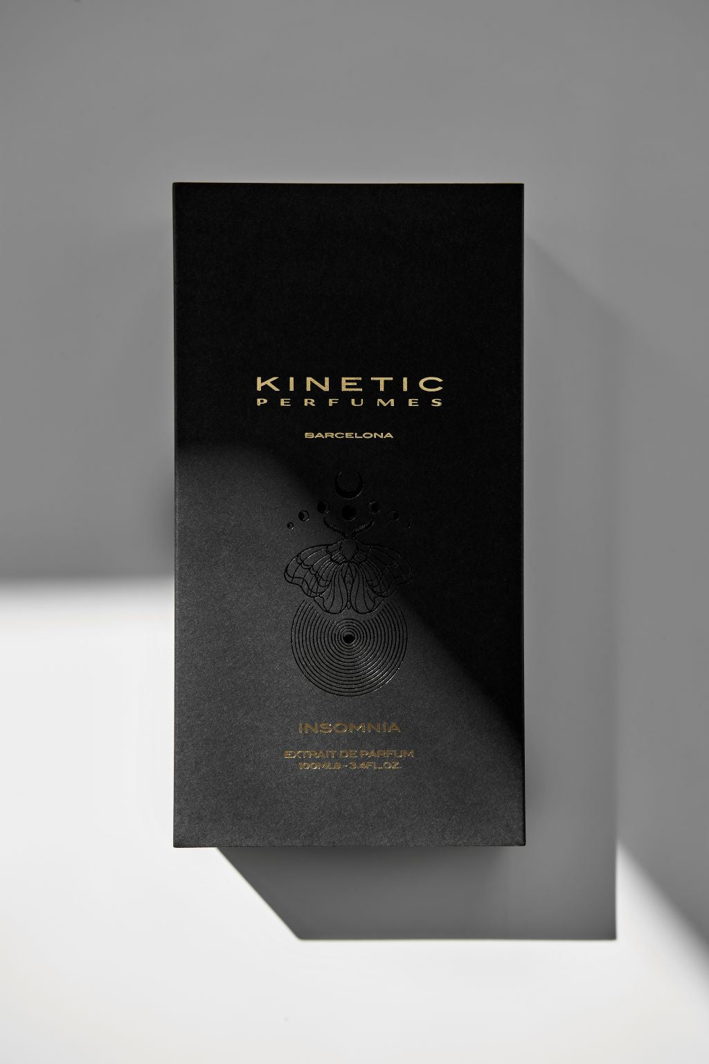 Kinetic Perfumes Insomnia Extrait de Parfum 100 ml – schwarze Box mit goldener Schrift und Motten-Prägung im Schattenlicht