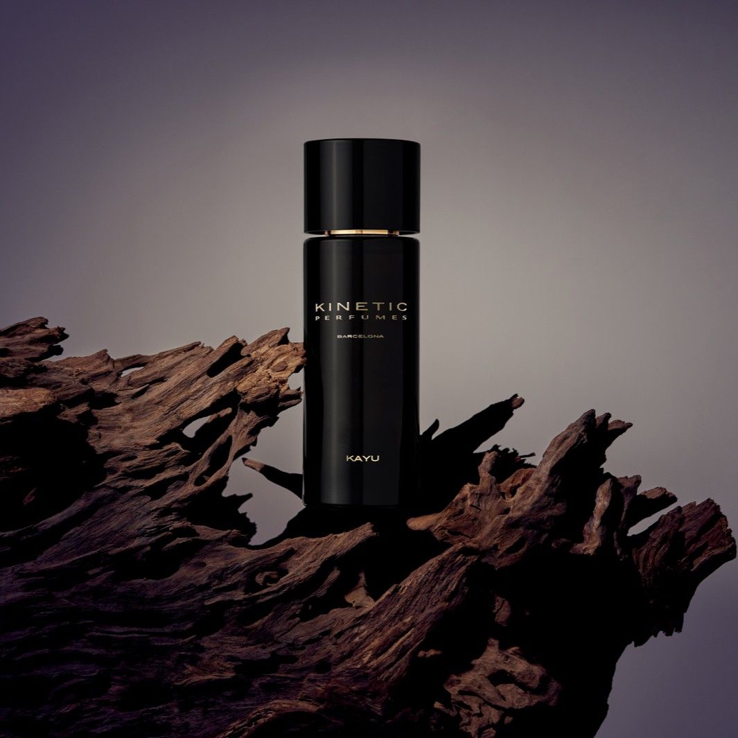 Kinetic Perfumes Kayu Extrait de Parfum 100 ml – schwarzer Flakon auf dunklem Treibholz vor grau-violettem Hintergrund