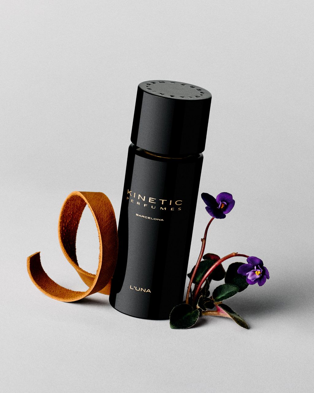 Kinetic Perfumes L'Una Extrait de Parfum 100 ml – schwarzer Flakon mit Veilchen und braunem Lederband auf Hellgrau