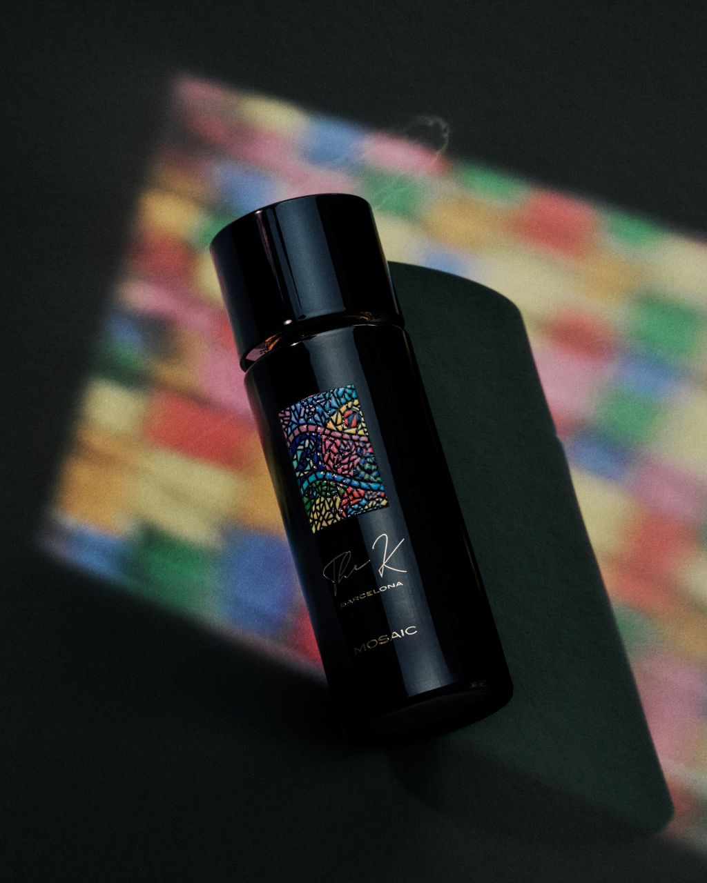 Kinetic Perfumes Mosaic Extrait de Parfum 100 ml – schräger Flakon mit Mosaik-Etikett in buntem Lichtmuster auf Dunkelgrün
