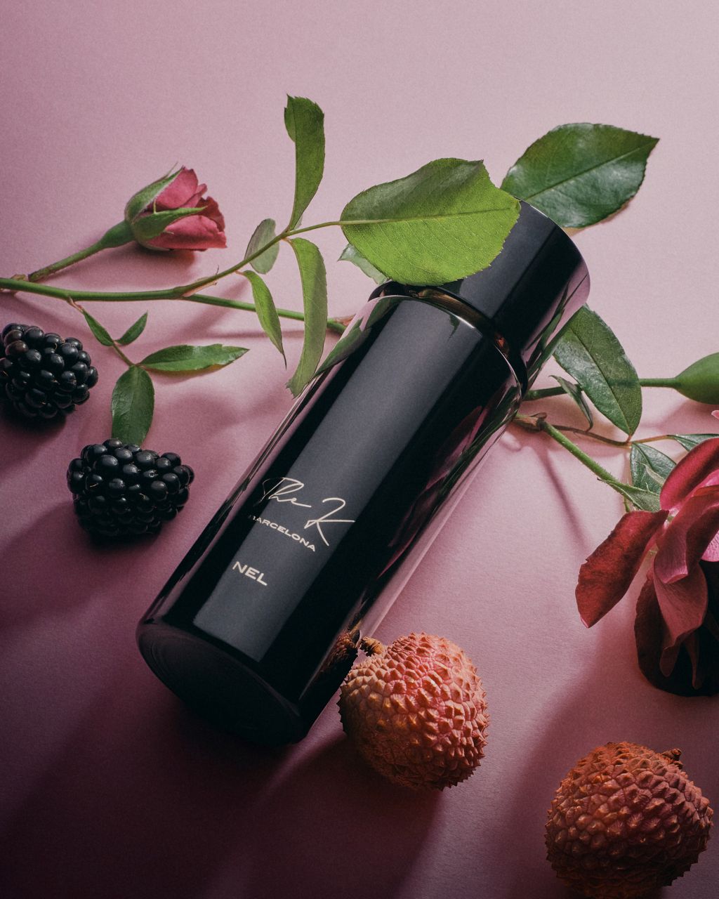 Kinetic Perfumes Nel Extrait de Parfum 100 ml – liegender Flakon mit Signatur zwischen Rosen, Brombeeren und Litschis auf Rosa