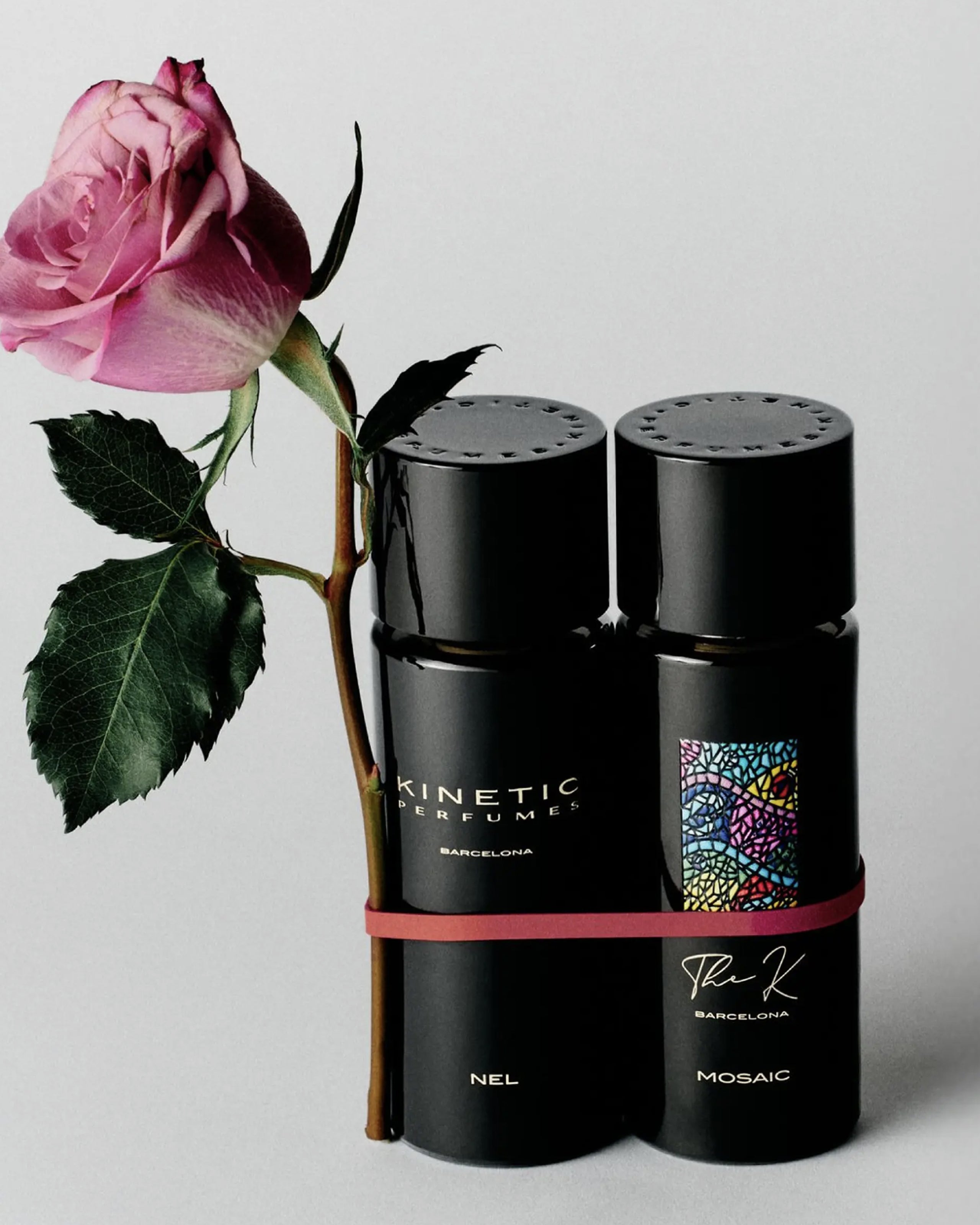 Kinetic Perfumes – deux flacons noirs, Nel et Mosaic, avec une rose rose