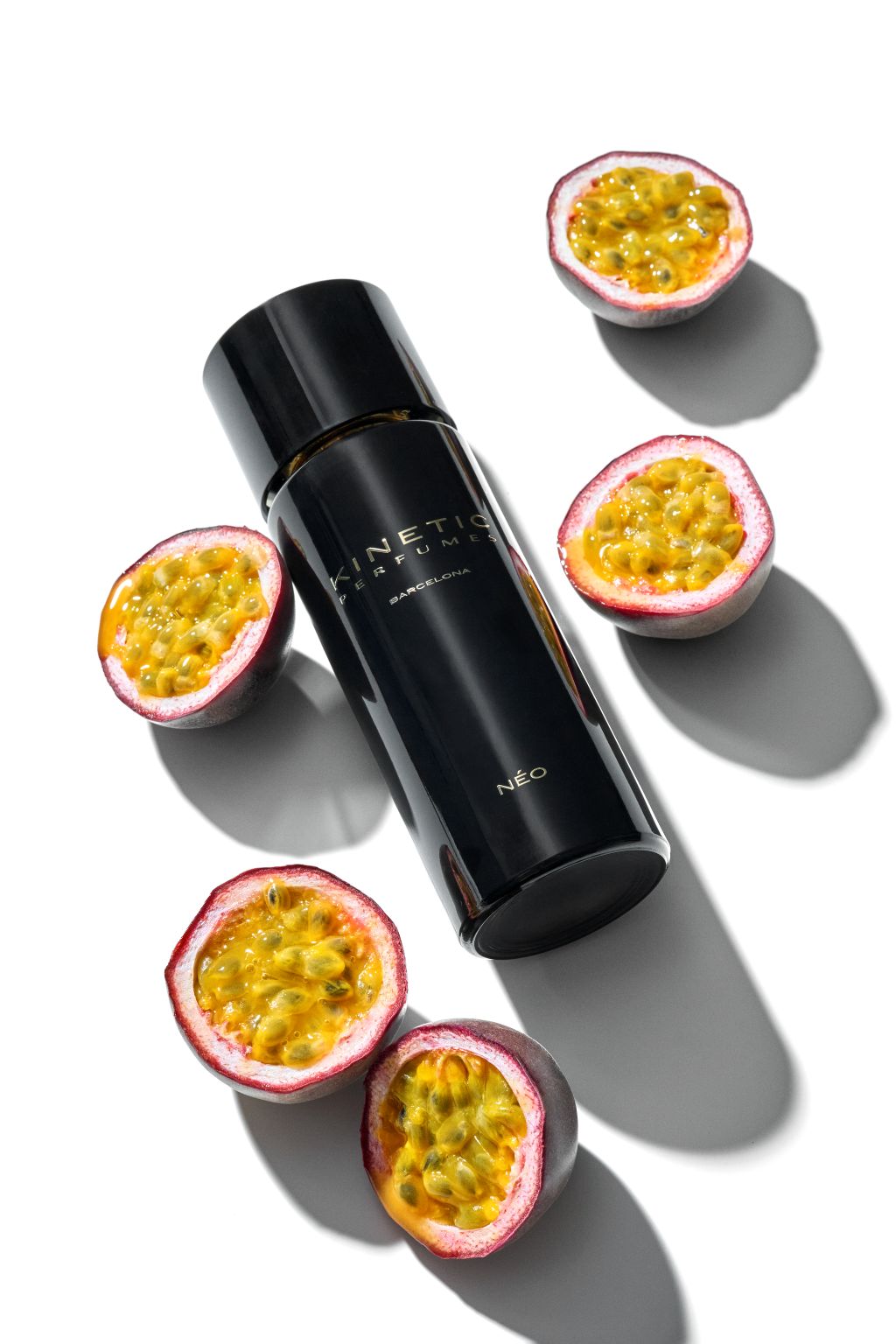 Kinetic Perfumes Néo Sillage Extrait de Parfum 100 ml – liegender schwarzer Flakon zwischen halbierten Maracujas auf Weiss