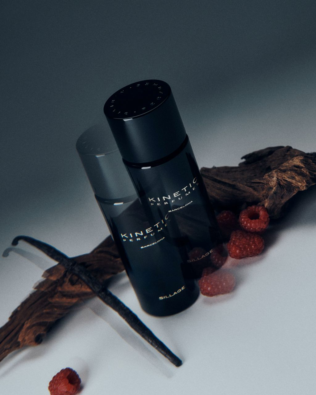 Kinetic Perfumes Sillage Extrait de Parfum 100 ml – zwei schwarze Flakons mit Holz, Vanilleschote und Himbeeren auf hellem Grund