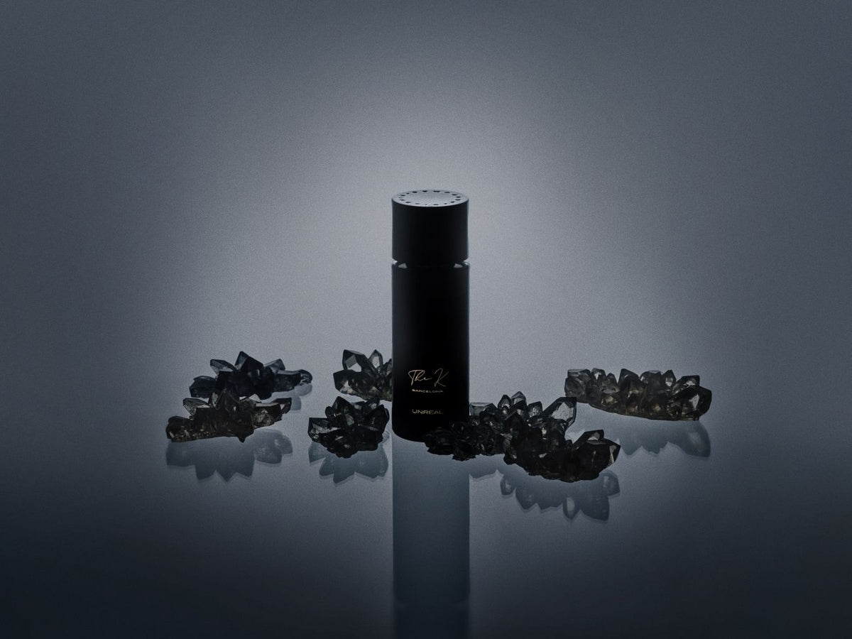 Kinetic Perfumes Unreal Extrait de Parfum 100 ml – schwarzer Flakon zwischen rauchgrauen Kristallen vor Dunkelgrau