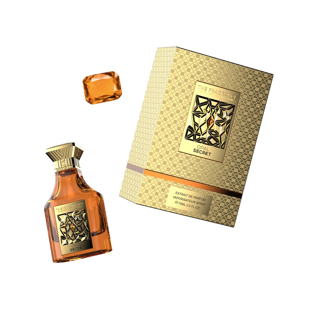 The Fragrance Opal Secret Extrait de Parfum 75 ml – bernsteinfarbener Flakon schräg neben orangem Edelstein und goldener Box
