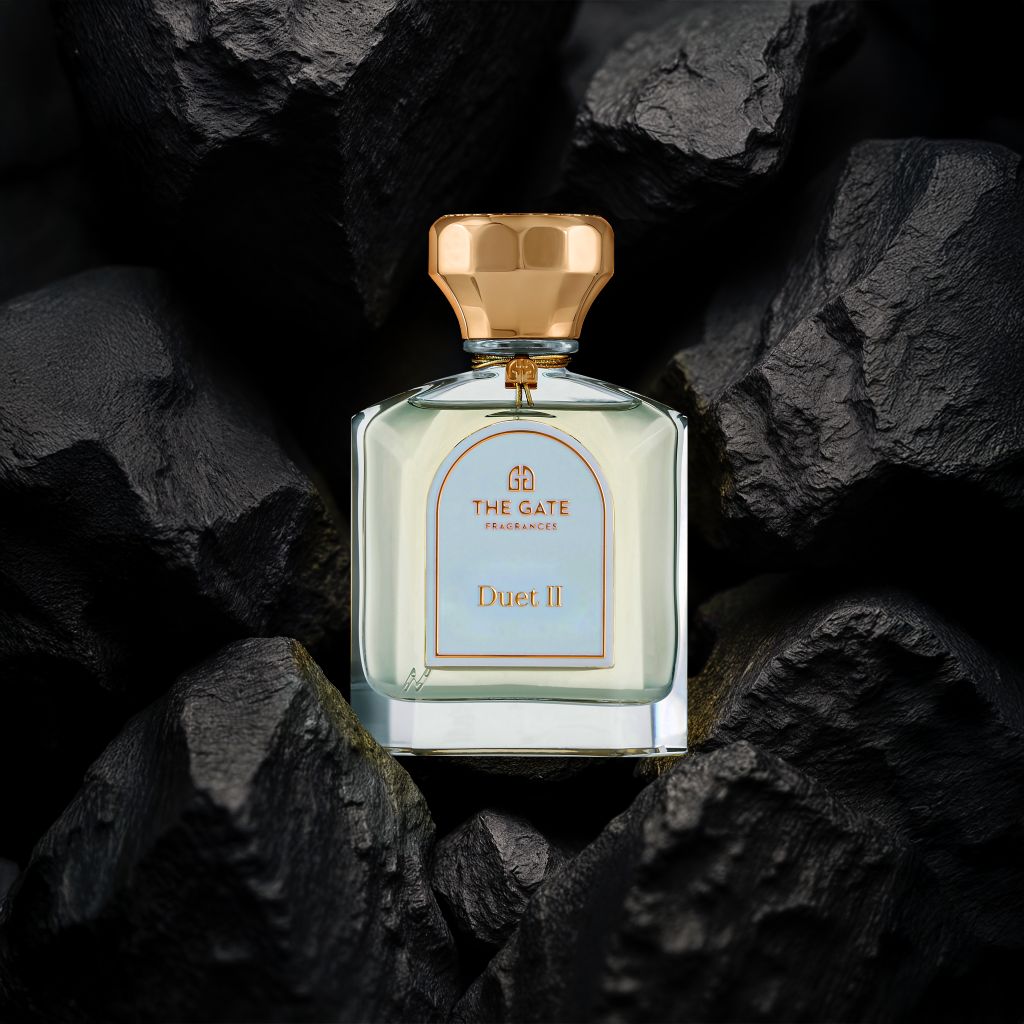 The Gate Duet II Extrait de Parfum 100 ml – Flakon mit hellblauem Etikett und roségoldener Kappe zwischen schwarzen Steinen