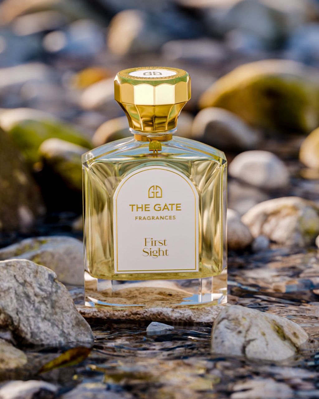The Gate First Sight Extrait de Parfum 100 ml – hellgoldener Flakon auf Stein im Bachbett mit Kieseln