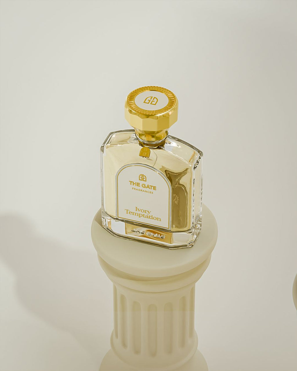 The Gate Ivory Temptation Extrait de Parfum 100 ml – hellgoldener Flakon von oben auf cremefarbener Säule, Kappe mit Logo