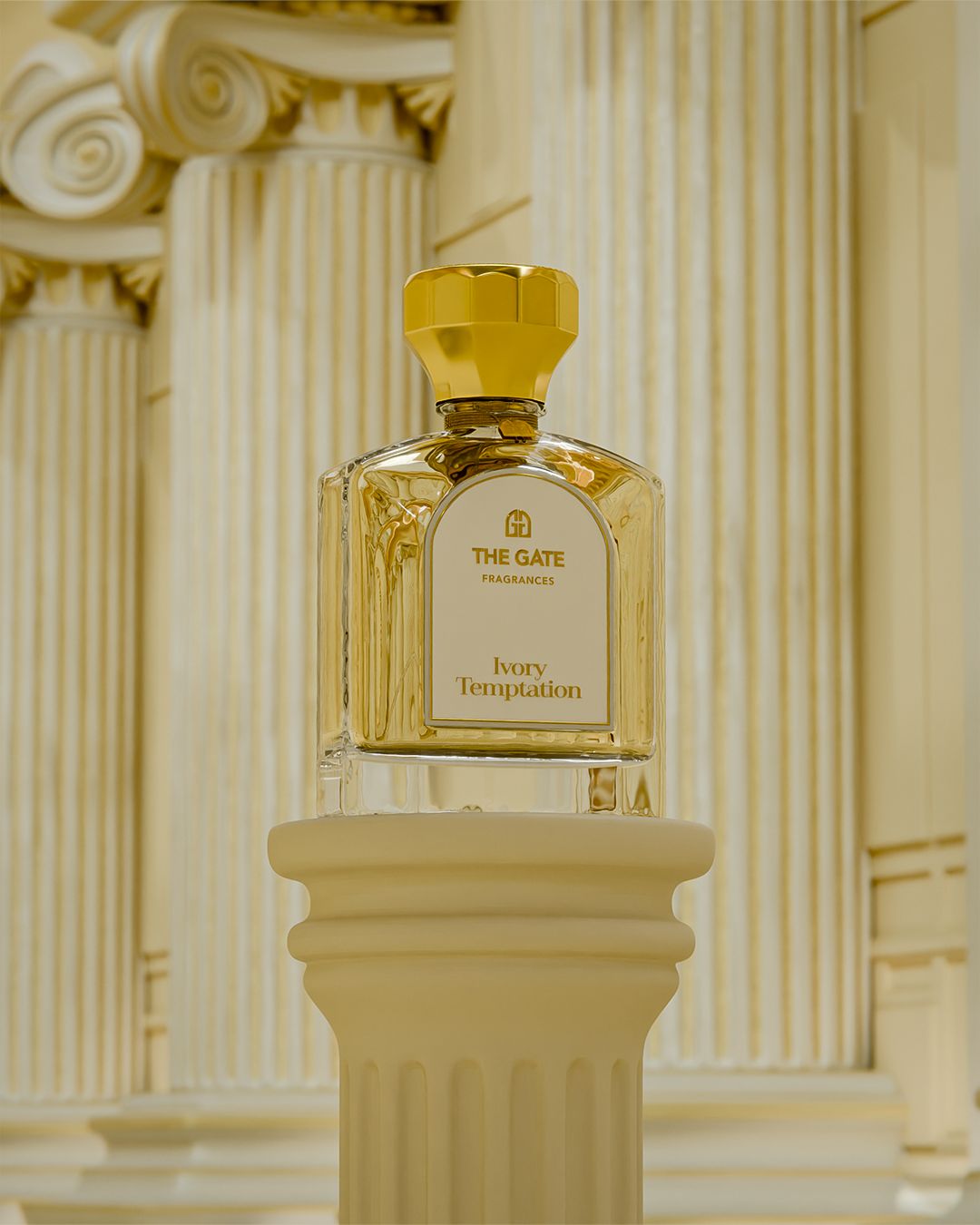 The Gate Ivory Temptation Extrait de Parfum 100 ml – hellgoldener Flakon auf Säule vor cremefarbenen ionischen Säulen