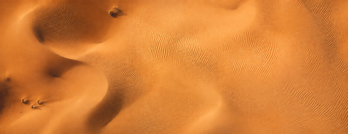 Orange Sanddünen der Wüste von oben mit feinen Windrippeln