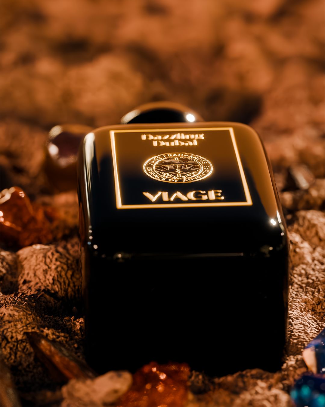 Viage Dazzling Dubai Extrait de Parfum 100 ml – Nahaufnahme liegender schwarzer Flakon mit goldenem Etikett zwischen Steinen