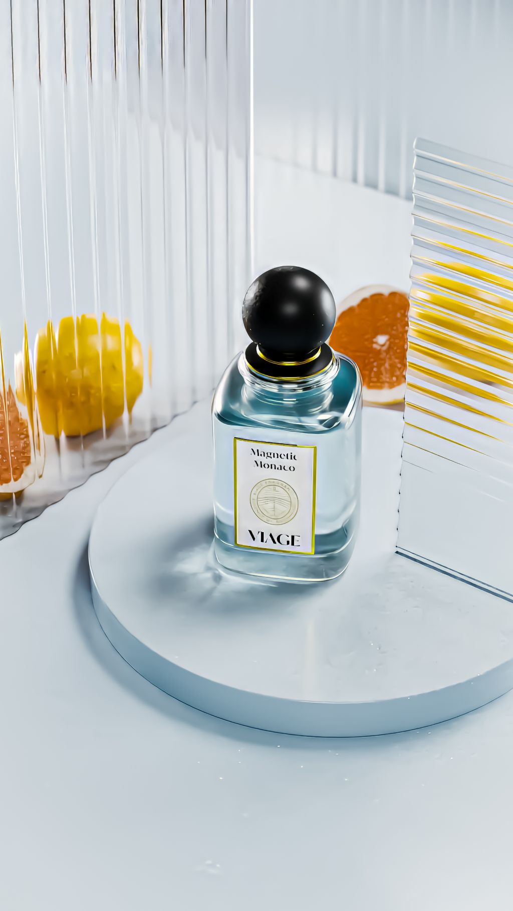 Viage Magnetic Monaco Extrait de Parfum 100 ml – Flakon mit hellblauem Inhalt auf weissem Podest, Riffelglas und Zitrusfrüchte