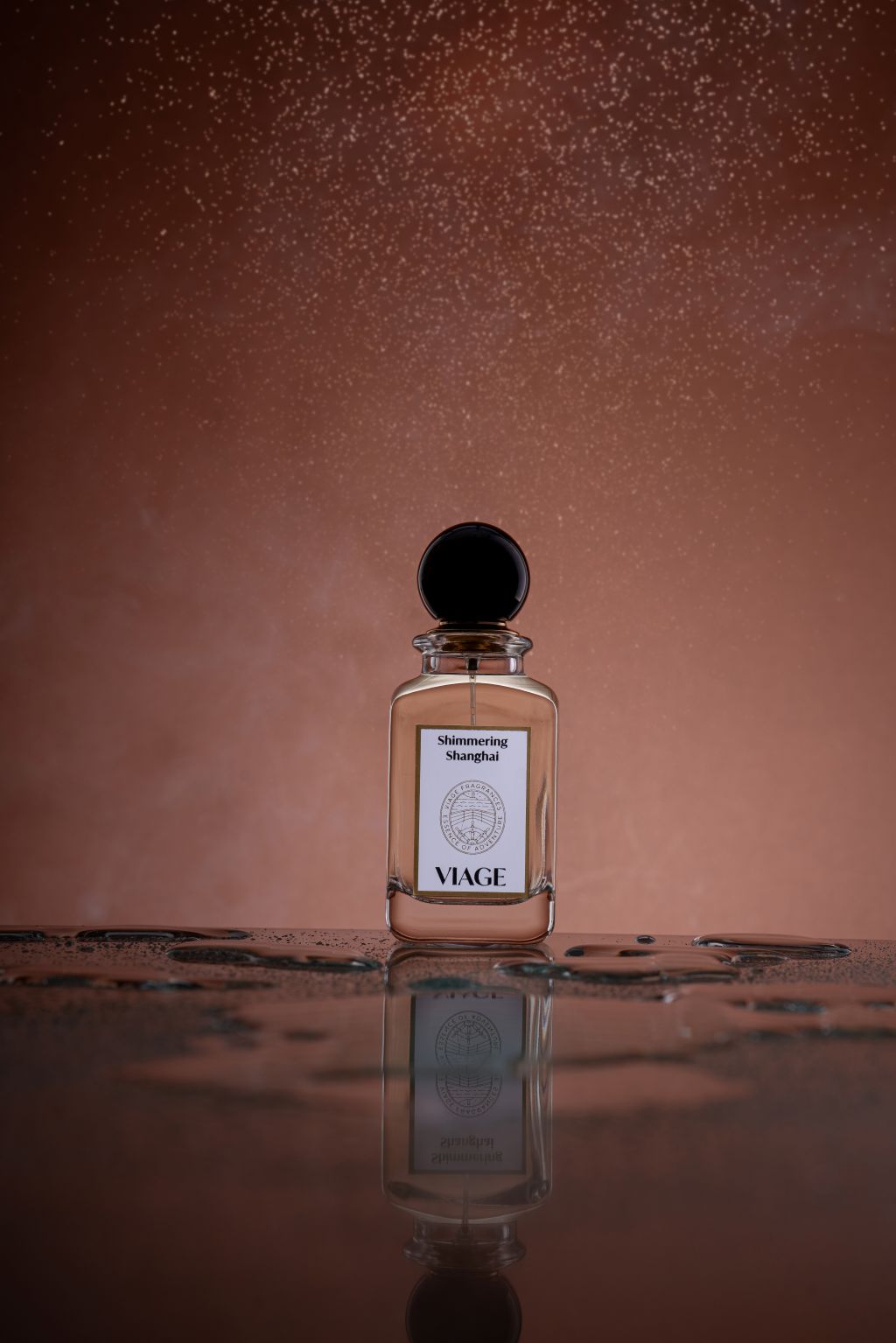 Viage Shimmering Shanghai Extrait de Parfum 100 ml – Flakon auf nasser spiegelnder Fläche vor kupferfarbenem Hintergrund