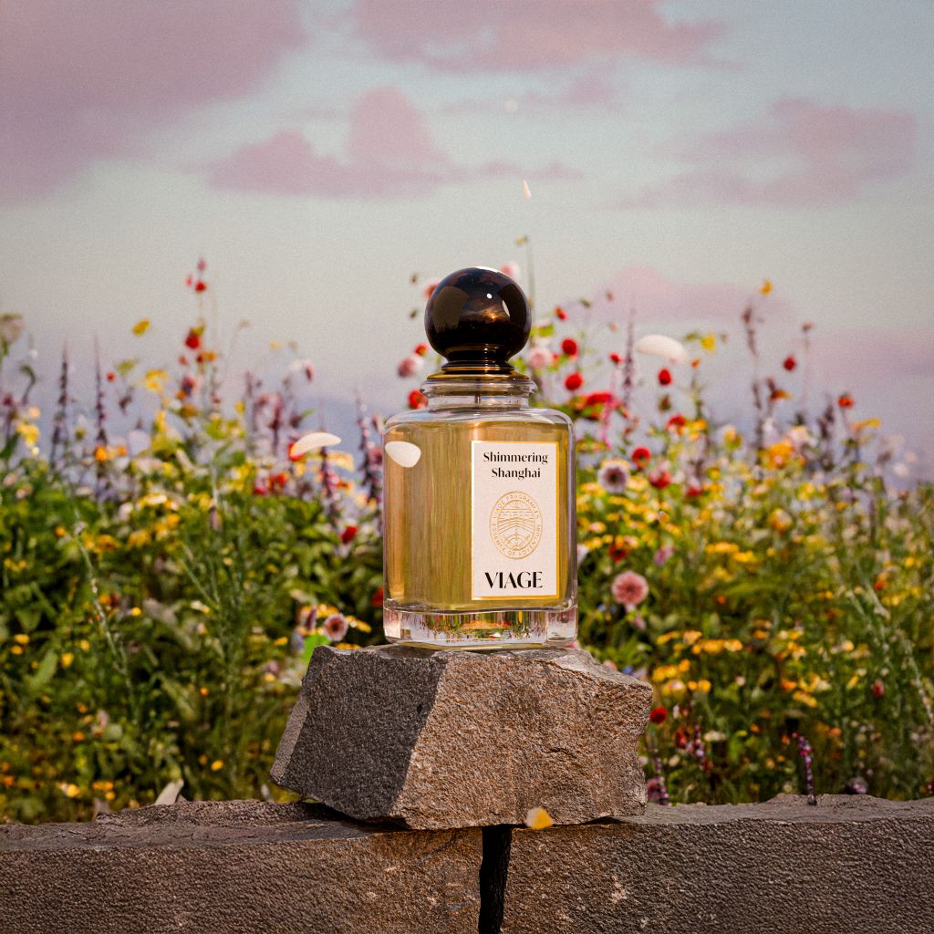 Viage Shimmering Shanghai Extrait de Parfum 100 ml – Flakon auf Steinmauer vor Wildblumenwiese im Abendlicht